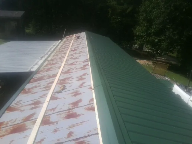 Old rusted panels beside newly installed green metal roofing — Wind Damage Roof Repair by Roofing Brothers in Huntington Woods