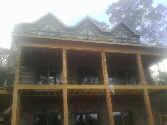 Dormers and porch framing on a large log home under construction — Roof Coating work by our crew in Huntington Woods