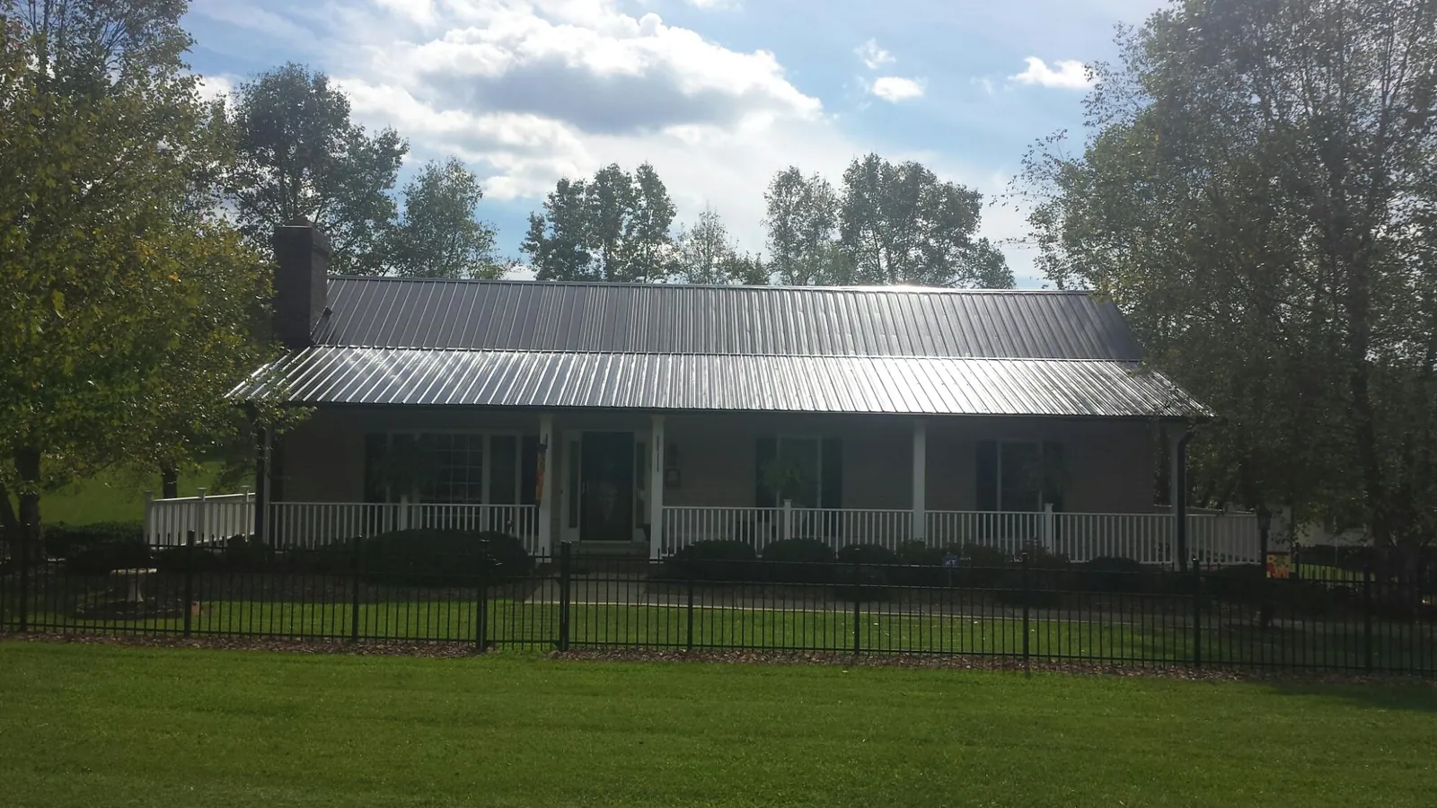 Gray metal roof on a brick ranch with a full width front porch — Gutter Guard Installation work by our crew in Huntington Woods