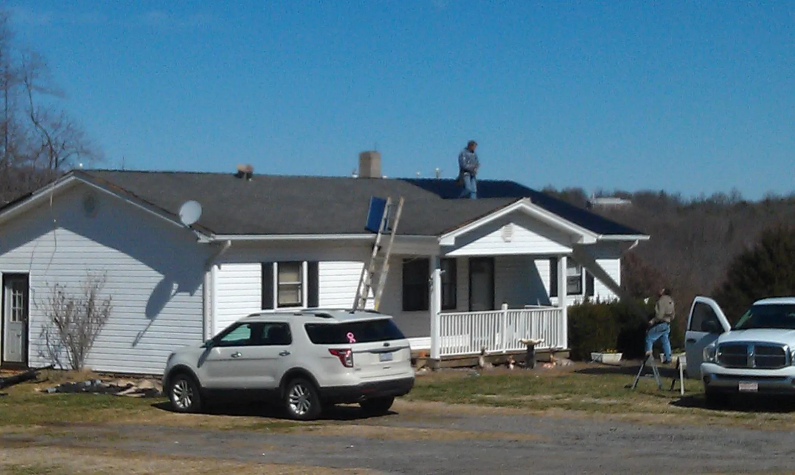 Roofers stripping shingles from a white ranch house roof in Huntington Woods