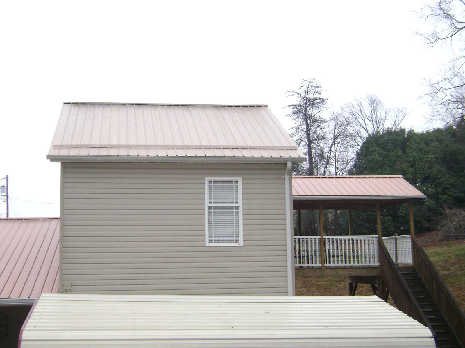Tan metal roofs on a two story addition and attached porch, from a Roof Replacement job in Huntington Woods