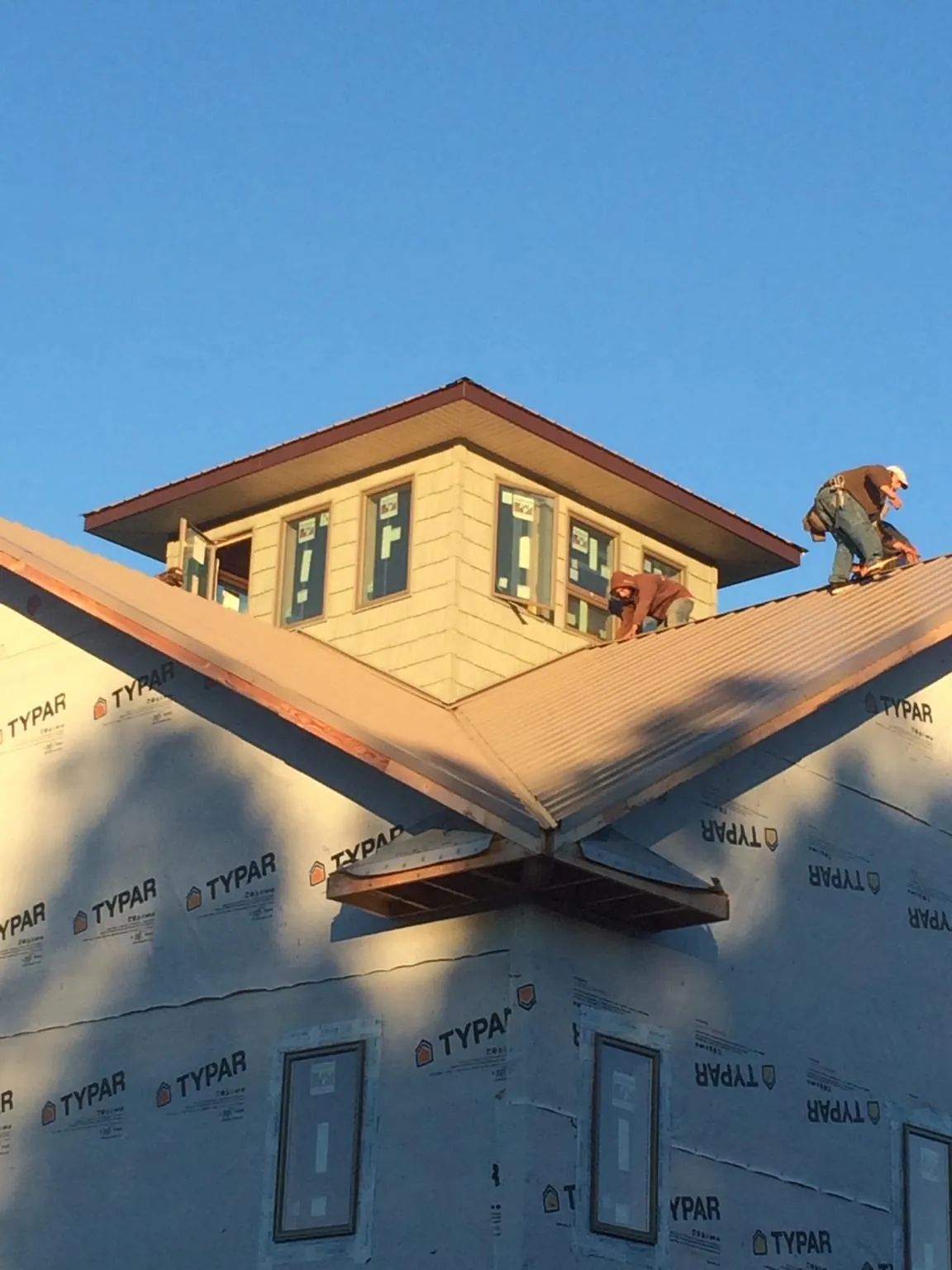 Roofers working around a rooftop cupola on a new metal roof at sunset — Roof Waterproofing in Huntington Woods by Roofing Brothers